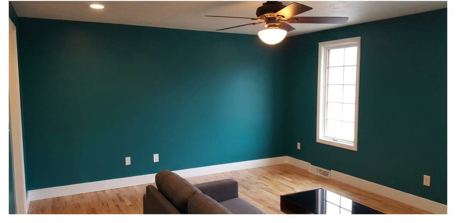 Finished room with smooth walls painted deep teal after drywall work